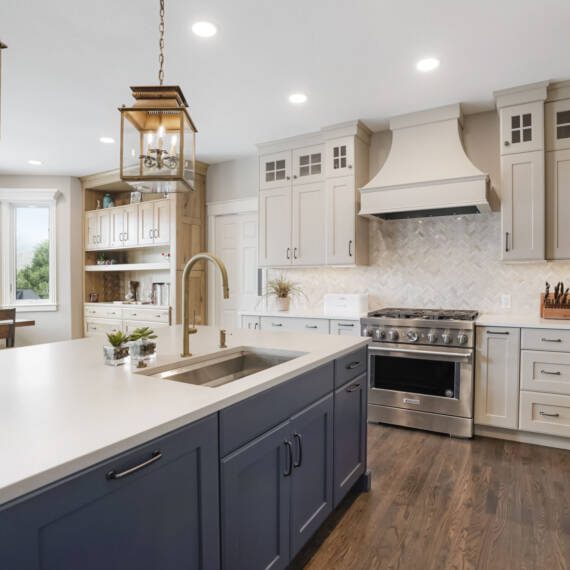 BKC Kitchen and Bath transitional kitchen with cream painted cabinets, blue painted center island, and natural hickory hutch