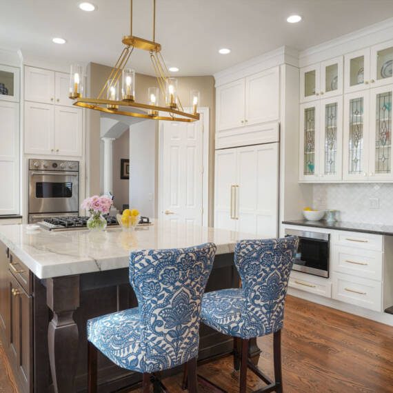 BKC Kitchen and Bath white traditional kitchen with dark wood center island and blue chair stools